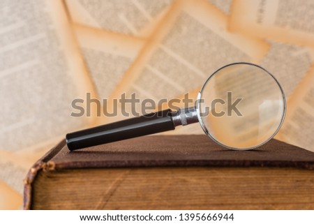 close-up magnifying glass place on old book, book pages background