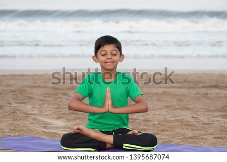 Boy doing meditation early morning on the beach Royalty-Free Stock Photo #1395687074