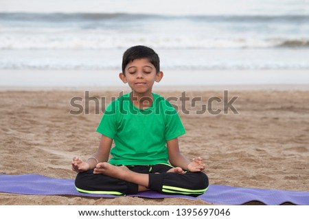 Boy doing meditation on the beach Royalty-Free Stock Photo #1395697046