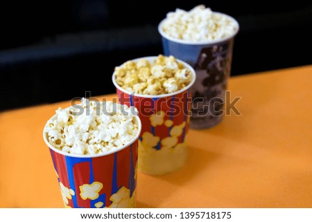 Photos of popcorn in cups. Popcorn near the cinema. Watching a movie, a cartoon with popcorn. Cinema session with popcorn