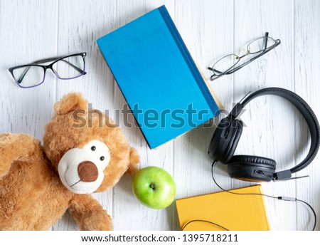 Photo of a stack of books with a bear, an apple and a place for an inscription on a wooden background. Back to school concept. Kids banner for text with books and bear. Concept on the topic of study