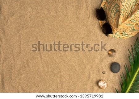 Stylish summer composition with green leaves, hat and sunglasses on a sand background. Artwork mockup with copy space