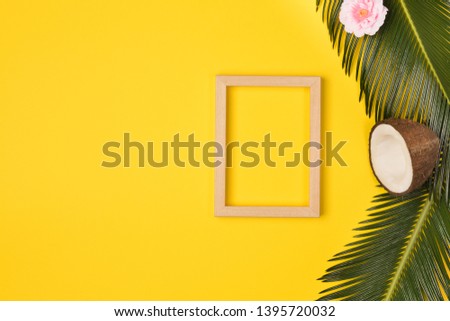 Summer composition with photo frame, green palm leaves, and cocunut on a yellow background. Artwork mockup with copy space
