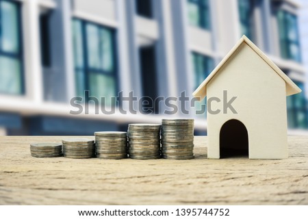 Property investment, home loan, house mortgage ,real estate financial concept. Money coin stack growing with wooden residential house model. Depicts a growth stock market about real estate and invest.