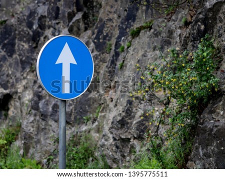 One way traffic sign, with stone behind