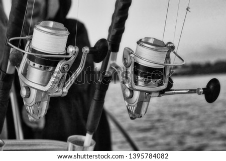 Fishing rods and reels on a family boat on a fishing vacation photographed in black and white. Royalty-Free Stock Photo #1395784082