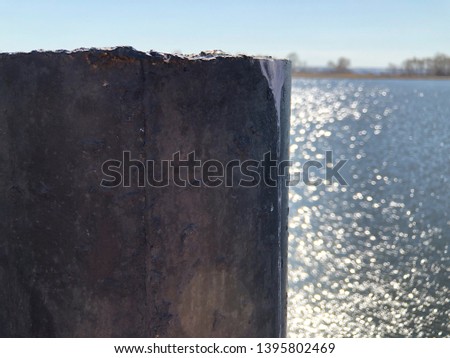 Pier support made of concrete pier poured into an iron pipe. Supports the pier over the water. Pier on the background of a river or sea.