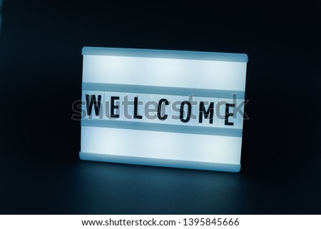Photo of a light box with text, WELCOME, over isolated dark background