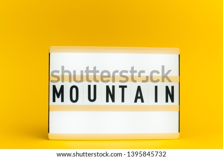 Photo of a light box with text, MOUNTAIN, on isolated yellow background