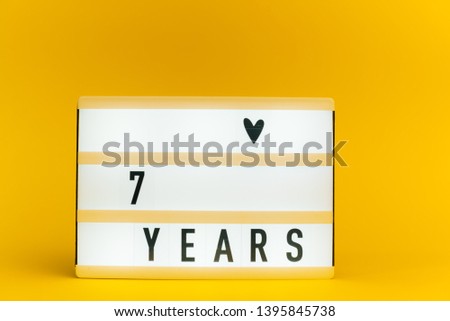 Photo of a light box with text, 7 YEARS, on isolated yellow background