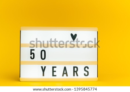 Photo of a light box with text, 50 YEARS, on isolated yellow background