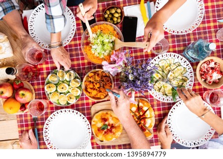 Cheerful checkered tablecloth for the sunday brunch. Caucasian people eating and drinking. Mix of vegetables food and salad.