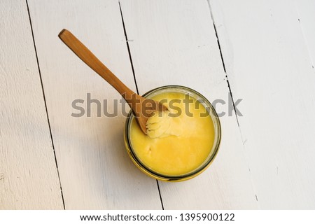 Ghee butter with wooden spoon on white background. Image with copy space, top view Royalty-Free Stock Photo #1395900122
