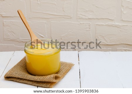 Ghee butter or clarified butter on white background with wooden spoon, copy space Royalty-Free Stock Photo #1395903836