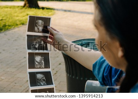 A pregnant woman looks at the photo of ultrasonography or diagnostic sonography. The concept of pregnancy, expect a child. The joy of being a future mother, problems during pregnancy.