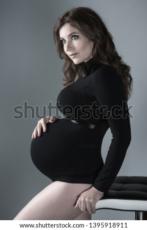pregnant woman on a gray background in black body