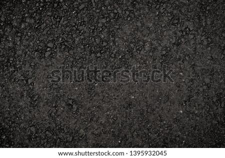 Texture of dark smooth asphalt with small black stones. Wallpaper for design, top view.