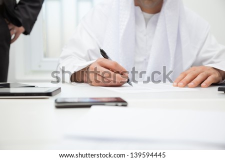 Close up of Arab businessman signing the contract. Focus is on hand