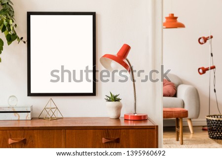 Stylish room of home interior with black mock up frame, design sofa, furnitures, vintage cupboard with elegant accessories, plants and red retro table lamp. Cozy home decor. Minimalistic concept.