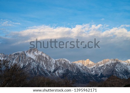 sunlight isolates peak in snowy mountain range Sierra Nevadas California