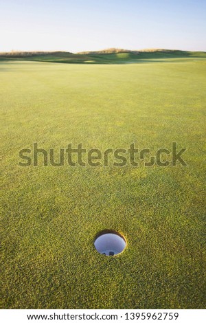 Close up picture of a hole on a golf course with expansive green grass