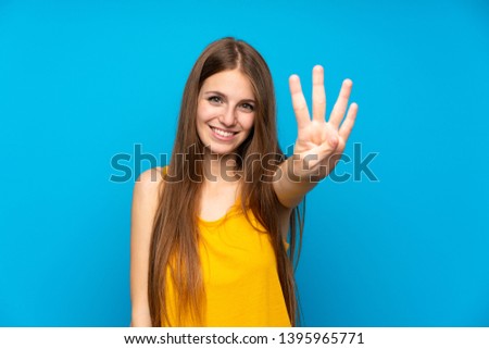 Young woman with long hair over isolated blue wall happy and counting four with fingers