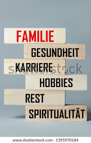 A list of wooden blocks lying on top of each other with a list of branches of human life in German, in the translation of the word: family, health, career, hobbies, relaxation, spirituality