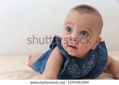 Beautiful baby girl with blue eyes looking at the camera smiling. Picture of an adorable baby girl with space for text. Baby looking to the side