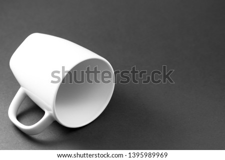Template of a white porcelain cup isolated on a black background lying horizontally wrapped in a play of shadows.
