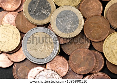 Different amounts of scattered European coins on a black background. Worn saving currencies, euros and cents.