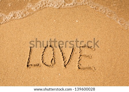 Love - written in sand on beach texture, soft wave of the sea