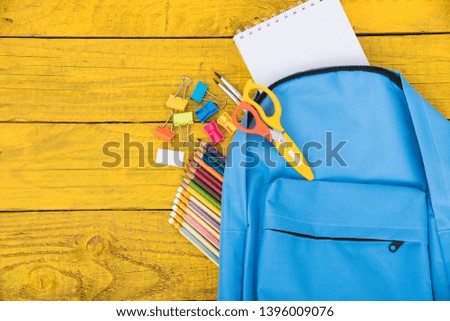 Top view Blue bag backpack for education children on yellow wooden  background back to school concept