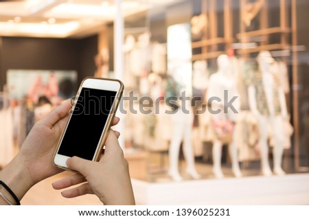 Online shopping, mobile banking, internet payment concept. Mockup image of young woman hand using blank screen mobile smart phone with blurred background fashion shop in shopping mall