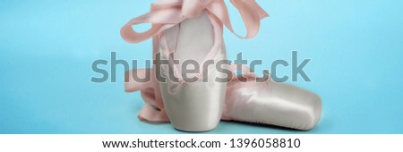 Pointe shoes ballet dance shoes with a bow of ribbons beautifully folded on a blue background.