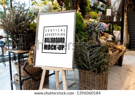 Mock up blank vertical advertising signboard in frame on wooden stand with clipping path in flower decoration shop, empty space for insert message or media advertisement indoo