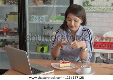 attractive asian female taking picture slice of strawberry cake with smartphone to uploading on social media at cafe and cake store