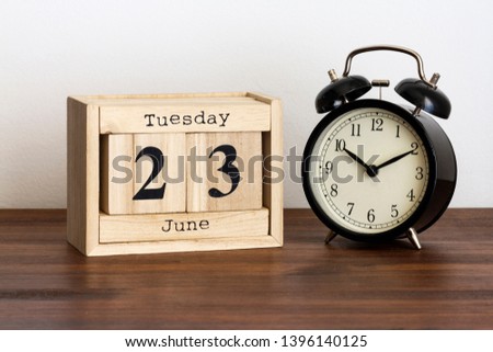 Wood calendar with date and old clock. Tuesday 23 June