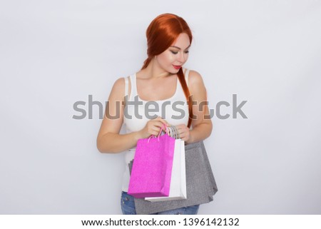 Photo of a beautiful amazing young redhead woman posing isolated over white background holding shopping bags