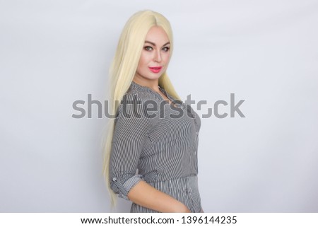 Portrait of positive blonde woman in trendy shirt and pants posing on camera isolated over white background
