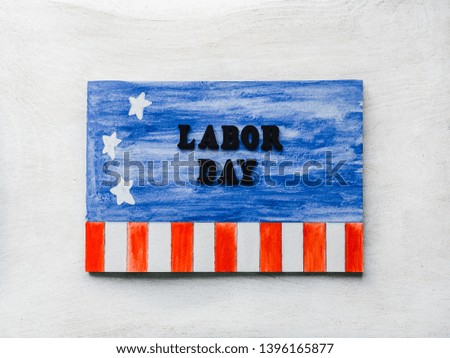 LABOR DAY. Notepad, American flag pattern and wooden letters of the alphabet on a white table. Close-up. Bright photo and space for your inscriptions. Congratulations to relatives, friends, colleagues