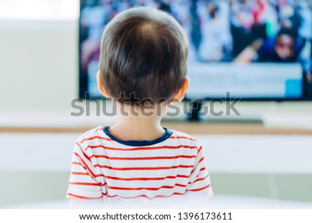 Back view of young boy is watching a television screen.Concept for a tv effect on children or a communication concept. 