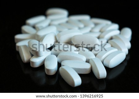 
White pills on a black background. A lot of psychedelic pills. Drug abuse and crime.