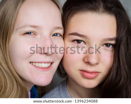 Two girls teen sisters or girlfriends brunette and blonde faces close-up portrait