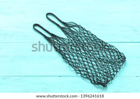 empty black mesh bag on turquoise wood background