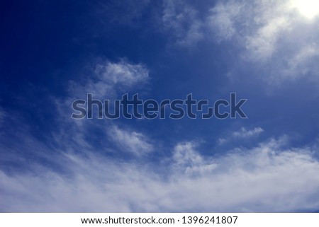 A deep blue sky with light white clouds background.