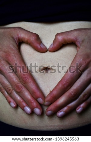 the shape of the heart created by the hands placed around the navel