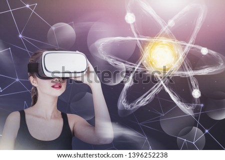 Young woman in casual clothes looking at glowing atom model. Concept of science, education and hi tech. Toned image double exposure