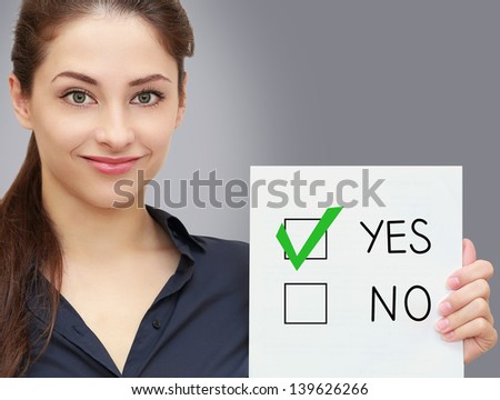 Business woman holding blank and voting for yes in option on grey background