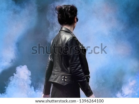 Beautiful woman in a leather jacket and sunglasses in red smoke