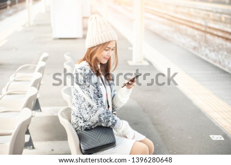 Beautiful woman is using smart phone on railway platform 
